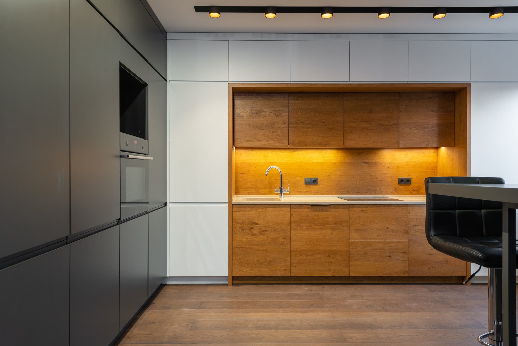 Grain matched wood cabinets set into a modern kitchen wall